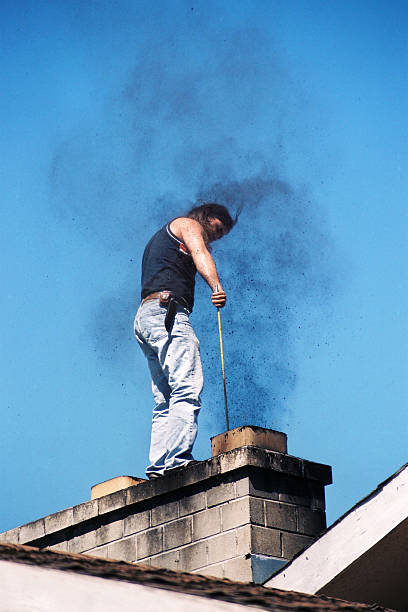 Young man standing on the roof of the house,cleaning the chimney